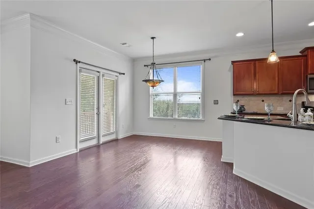 a kitchen with stainless steel appliances granite countertop a refrigerator a sink dishwasher a stove and white countertops with wooden floor