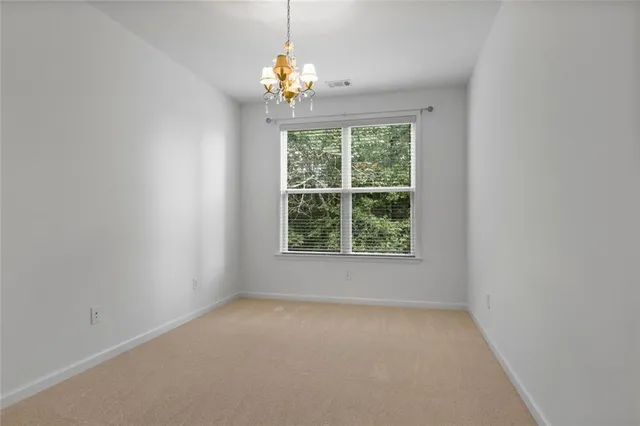 an empty room with chandelier fan and windows