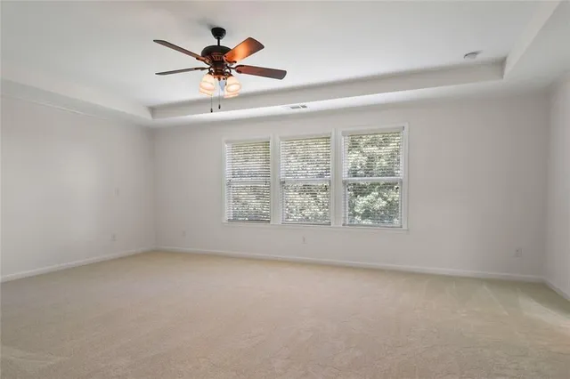 an empty room with windows and ceiling fan