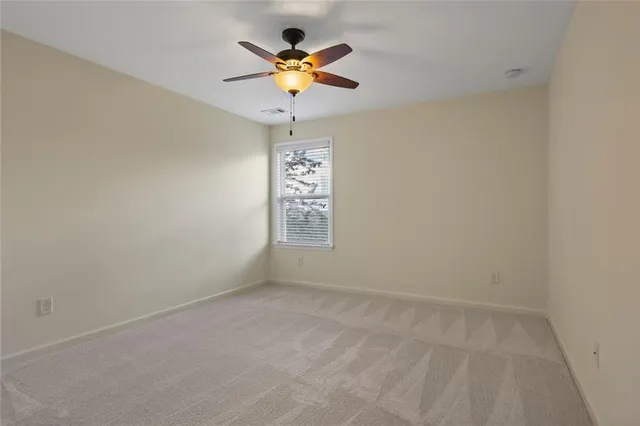a view of an empty room with window and chandelier fan