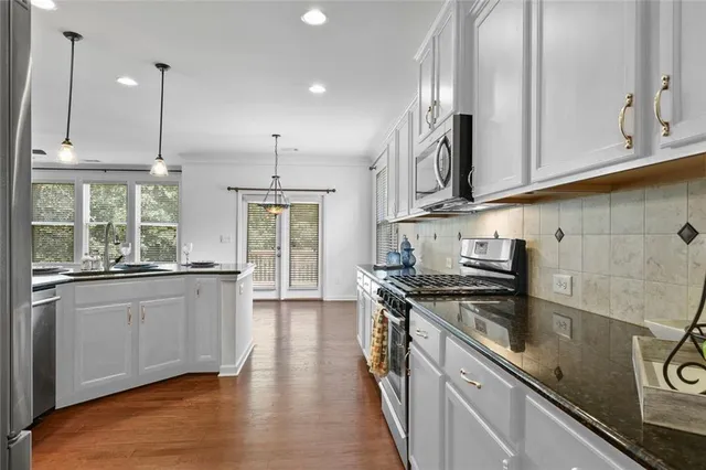 a kitchen with stainless steel appliances granite countertop a sink a stove and a wooden floors
