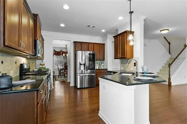a kitchen with stainless steel appliances granite countertop a sink a stove and a refrigerator