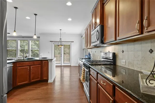 a kitchen with stainless steel appliances granite countertop a sink a stove and a wooden floors