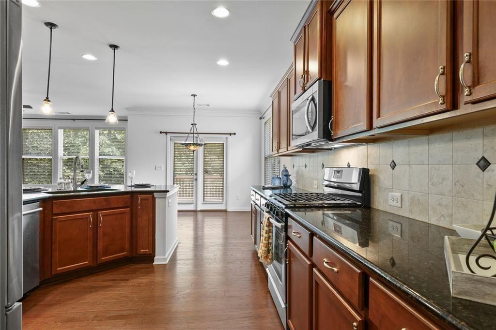 3935 Silver Springs Road Cumming, GA 30041 - Photo 9 of 37 a kitchen with stainless steel appliances granite countertop a sink a stove and a wooden floors