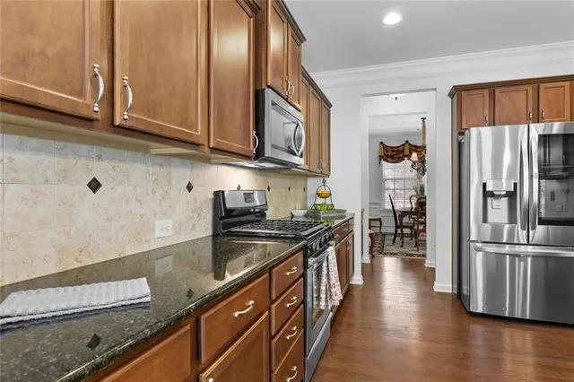 a kitchen with stainless steel appliances granite countertop a refrigerator a stove and a sink