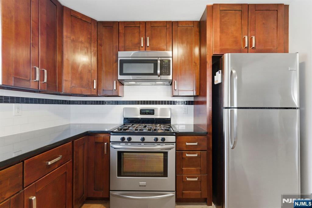 50-56 High Street, Unit 2 Passaic, NJ 07055 - Photo 11 of 30 a kitchen with stainless steel appliances granite countertop a refrigerator stove and microwave