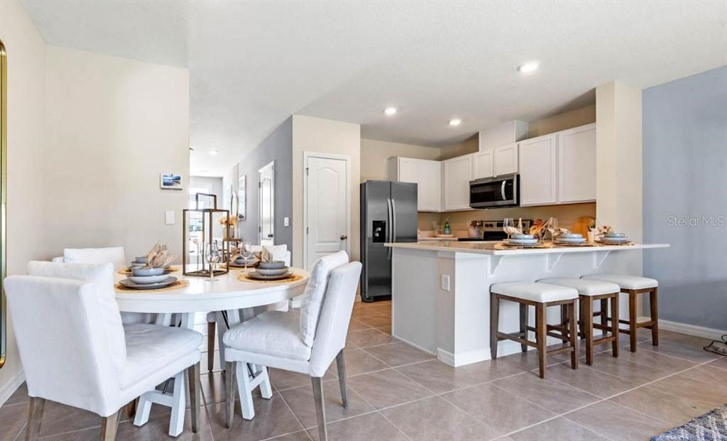 1642 Rock Elm Road Davenport, FL 33837 - Photo 3 of 27 a kitchen with stainless steel appliances kitchen island granite countertop a dining table chairs and a refrigerator