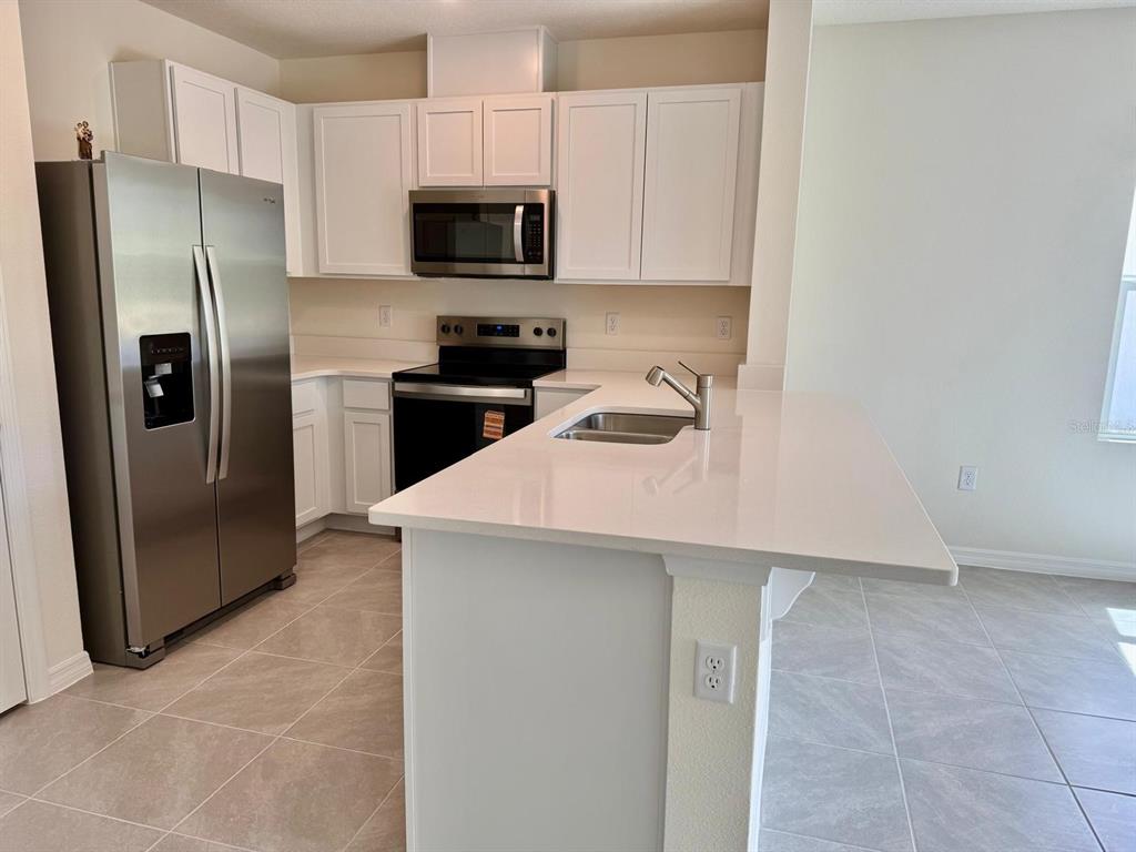 1642 Rock Elm Road Davenport, FL 33837 - Photo 6 of 27 a kitchen with stainless steel appliances a refrigerator a sink a stove a microwave and cabinets