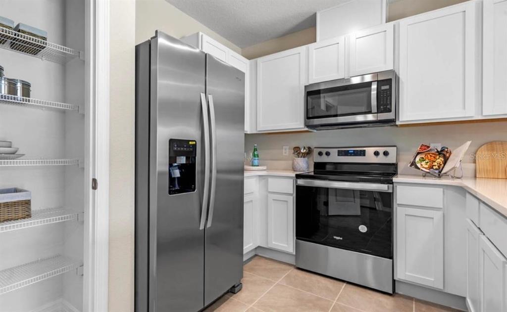 1642 Rock Elm Road Davenport, FL 33837 - Photo 7 of 27 a kitchen with stainless steel appliances granite countertop a refrigerator and a stove top oven
