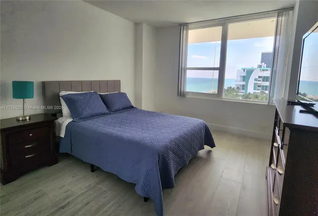 a bedroom with a bed and a flat tv screen on dresser