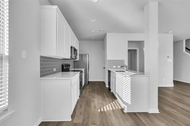 a kitchen with white cabinets and stainless steel appliances