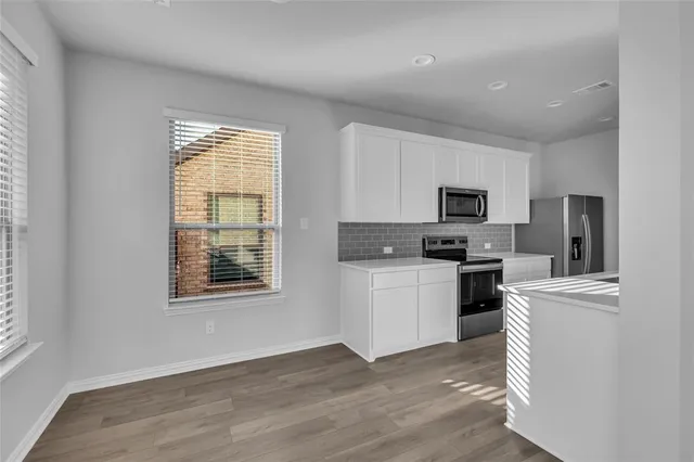 a kitchen with stainless steel appliances a stove top oven a sink a refrigerator a window