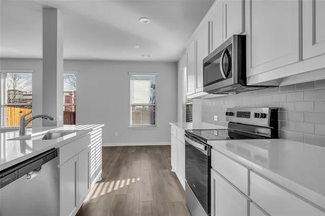 a kitchen with stainless steel appliances granite countertop a stove a sink and a microwave