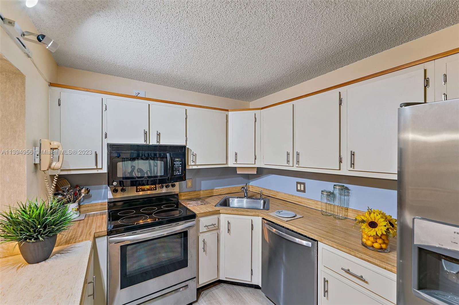 307 Pine Ridge Circle, Unit D2 Greenacres, FL 33463 - Photo 14 of 41 a kitchen with a sink stove and white cabinets