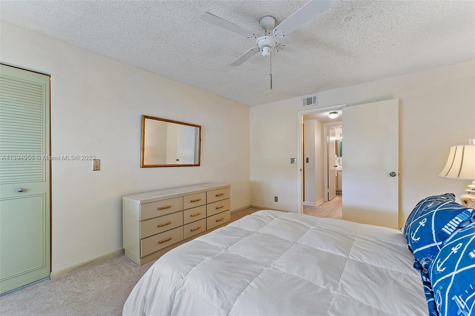 307 Pine Ridge Circle, Unit D2 Greenacres, FL 33463 - Photo 20 of 41 a bedroom with a bed a chandelier and a dresser