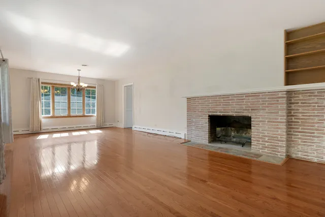an empty room with wooden floor fireplace and windows