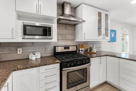 a kitchen with stainless steel appliances granite countertop white cabinets and a stove a oven with white countertops