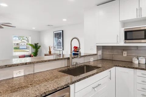 a kitchen with granite countertop a sink and a stove top oven