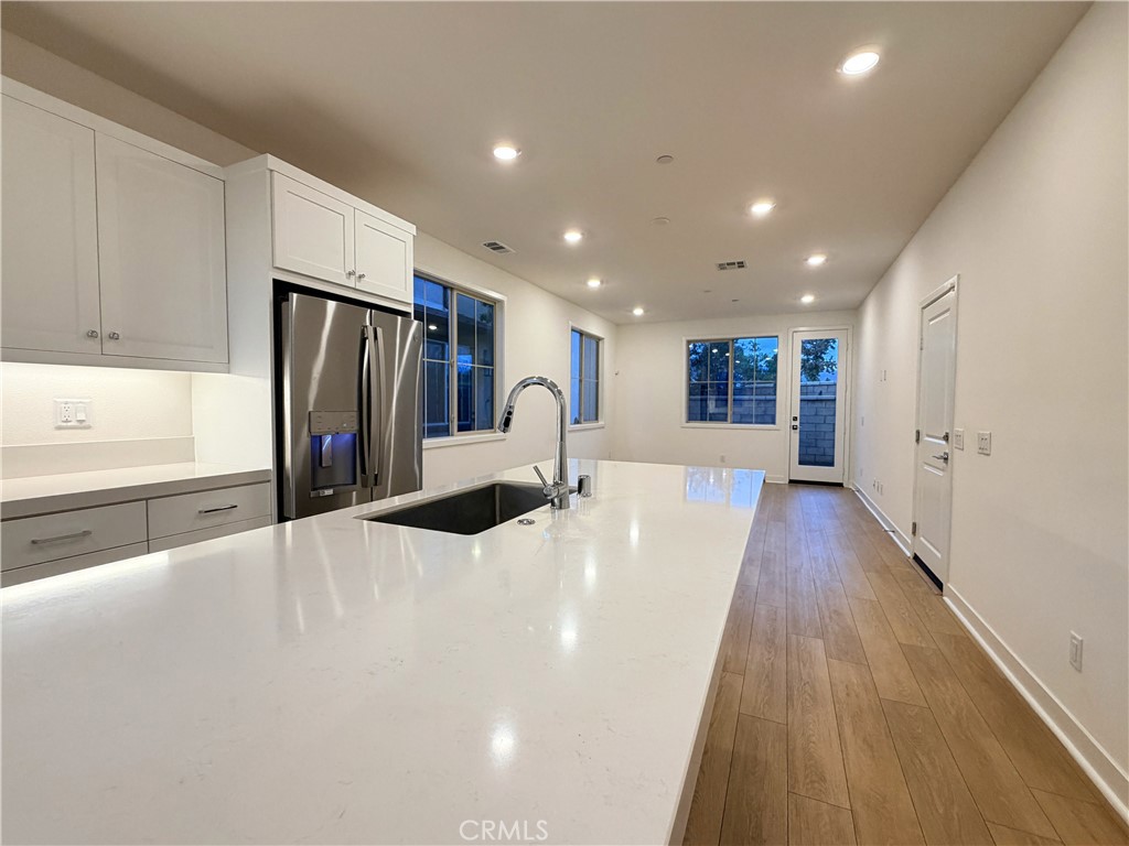 1643 Rosewell Road West Covina, CA 91791 - Photo 7 of 27 a large white kitchen with wooden floor and a refrigerator