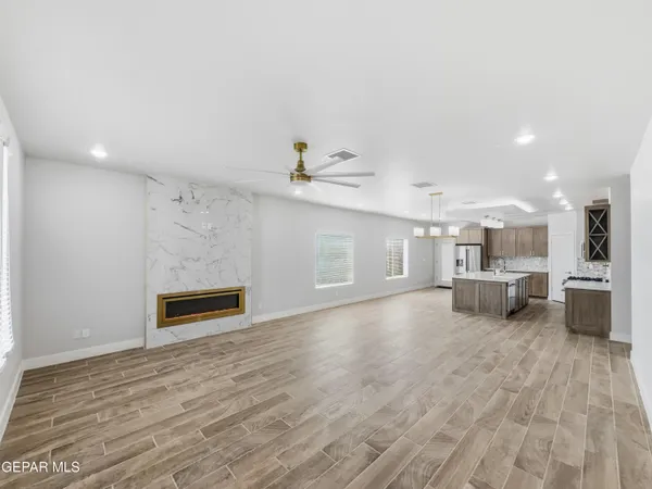 a view of kitchen and empty room with wooden floor