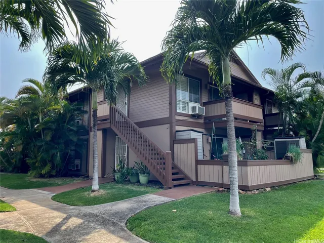 a view of a house with a small yard plants and palm trees