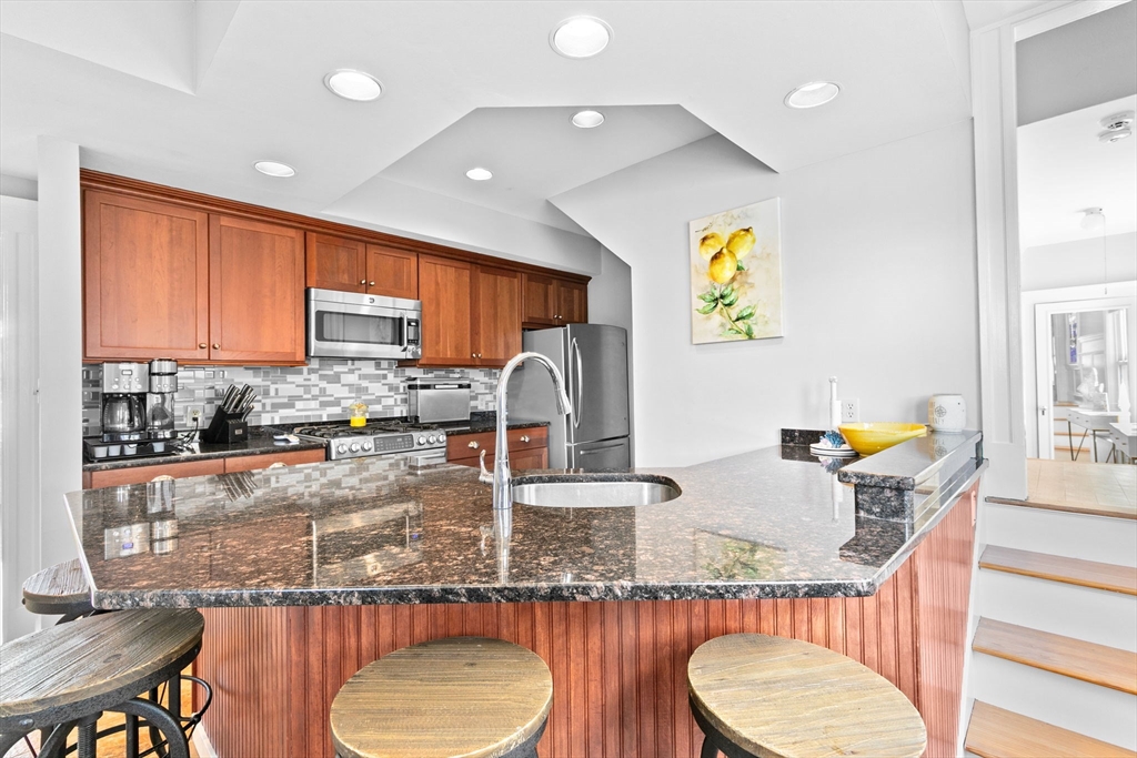 79 F Street Hull, MA 02045 - Photo 22 of 42 a kitchen with granite countertop a sink a stove and a wooden cabinets