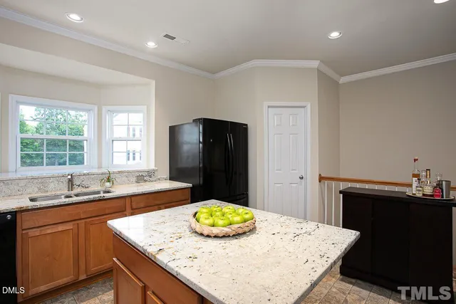 a kitchen with a sink a kitchen island a stove a refrigerator and a dining table