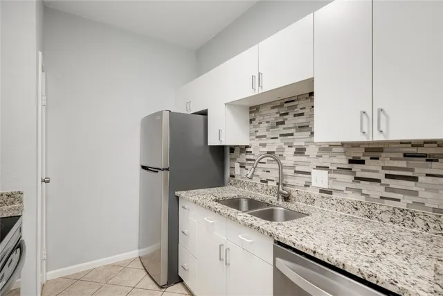 a kitchen with granite countertop a sink and a refrigerator