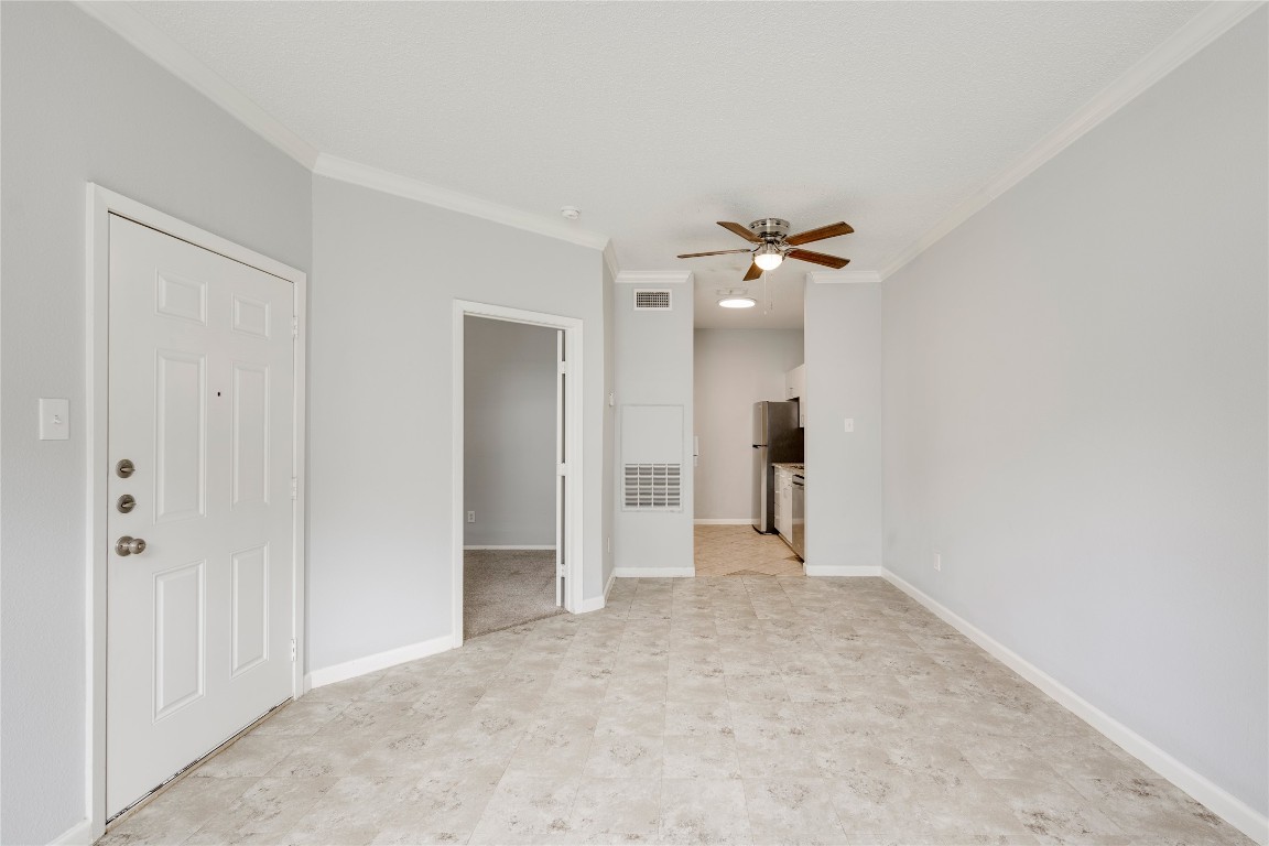 12166 Metric Boulevard, Unit 129 Austin, TX 78758 - Photo 17 of 38 Unfurnished living room featuring crown molding and ceiling fan