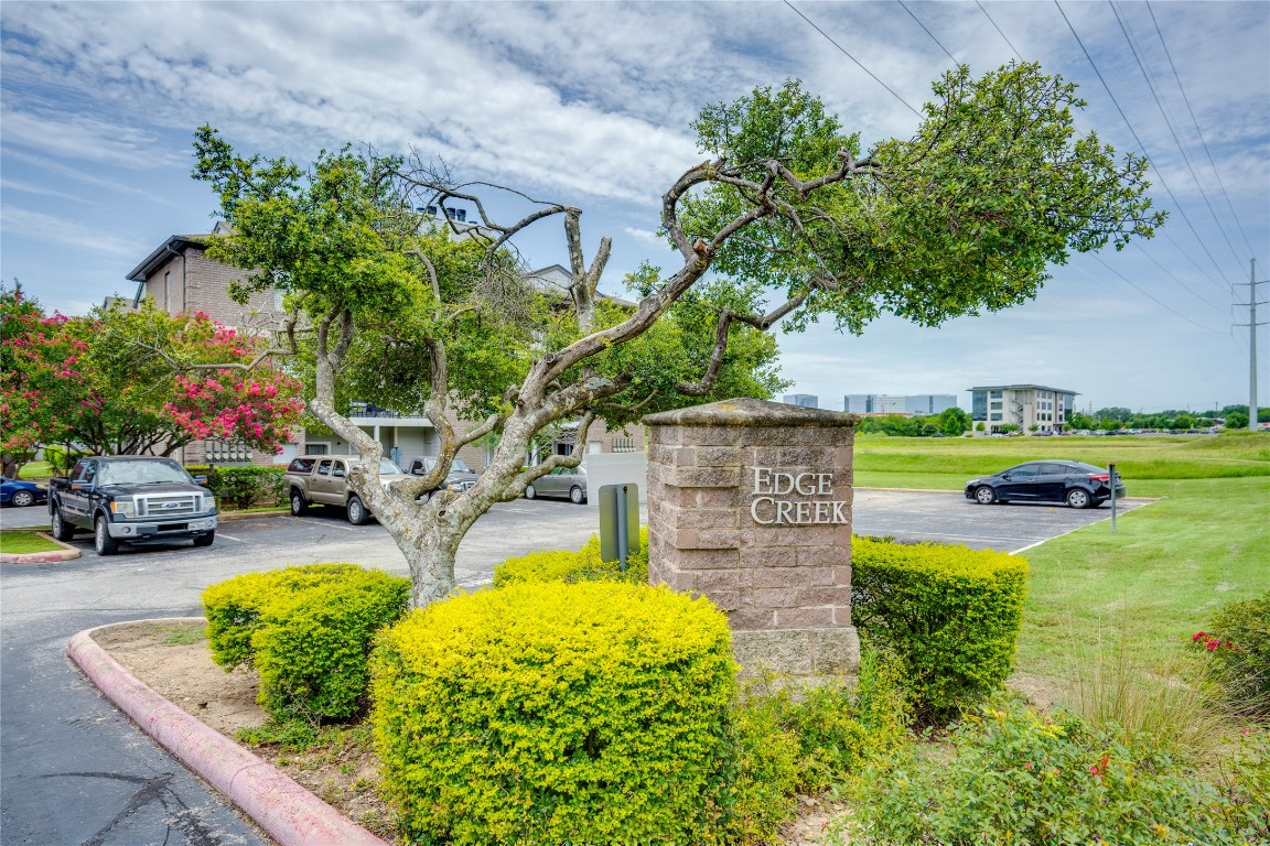 12166 Metric Boulevard, Unit 129 Austin, TX 78758 - Photo 38 of 38 Community / neighborhood sign featuring uncovered parking and a yard