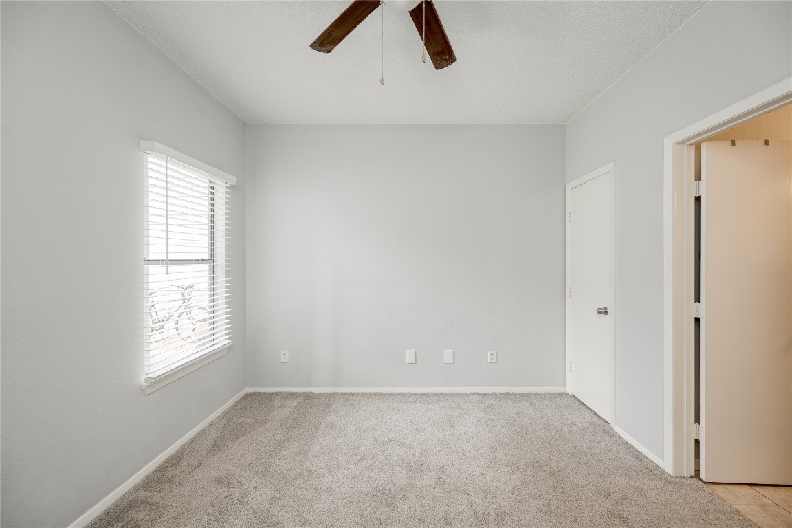 12166 Metric Boulevard, Unit 129 Austin, TX 78758 - Photo 10 of 38 Unfurnished bedroom featuring multiple windows, light carpet, and a ceiling fan