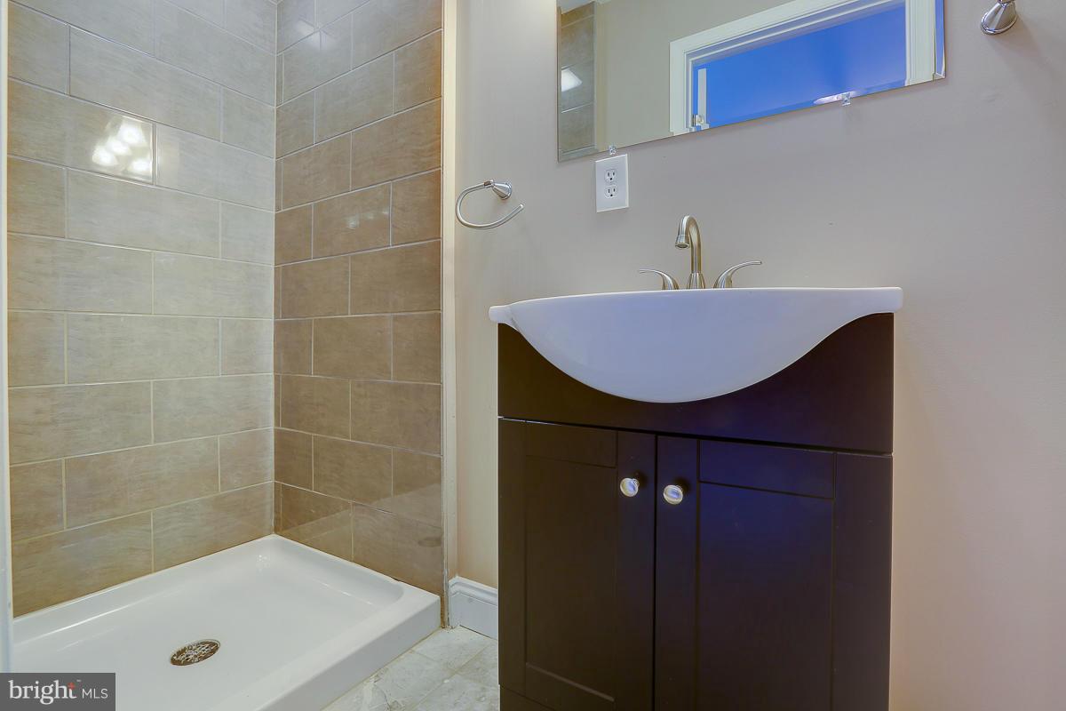 1533 Weyburn Road Baltimore, MD 21237 - Photo 21 of 30 a bathroom with a sink a shower a mirror and a bathtub