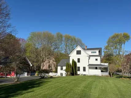 a view of a white house with a big yard and large trees