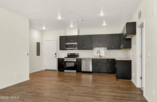 a large kitchen with stainless steel appliances granite countertop a stove a sink a refrigerator and a microwave