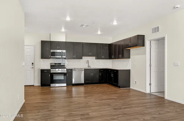 a large kitchen with stainless steel appliances granite countertop a stove a refrigerator a sink a microwave and wooden cabinets