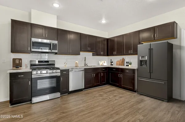 a kitchen with granite countertop a refrigerator and a stove top oven