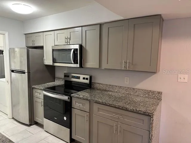 a kitchen with stainless steel appliances granite countertop a refrigerator stove and microwave