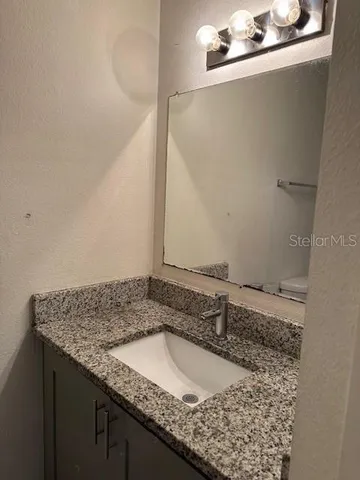 a bathroom with a granite countertop sink and a mirror