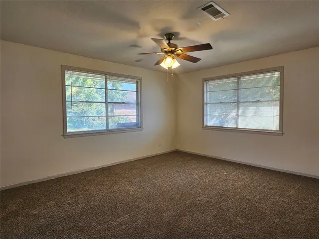 an empty room with windows and fan