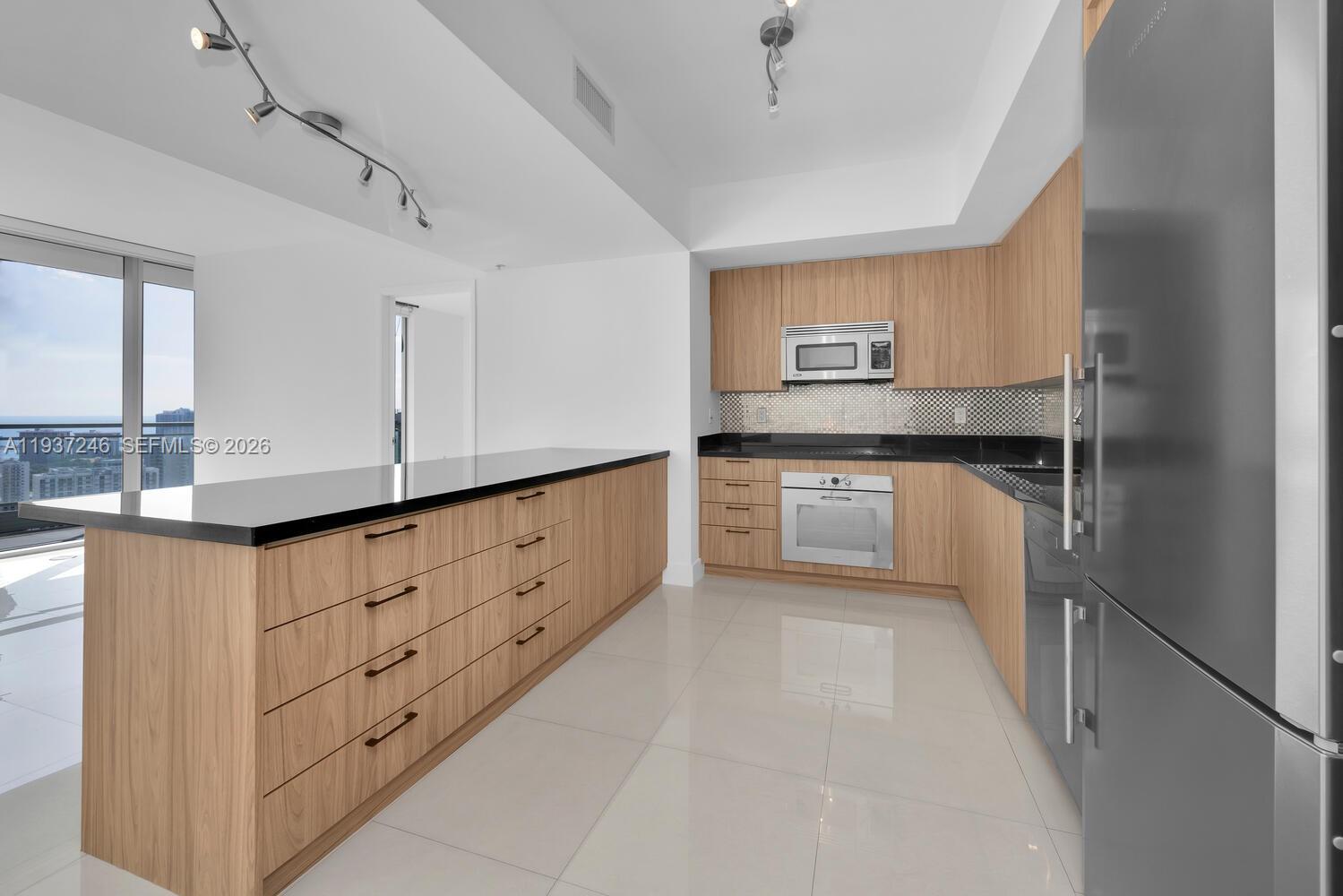 92 Southwest 3rd Street, Unit 3904 Miami, FL 33130 - Photo 6 of 23 a kitchen with granite countertop cabinets and window