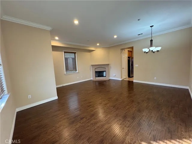 an empty room with wooden floor fireplace and windows