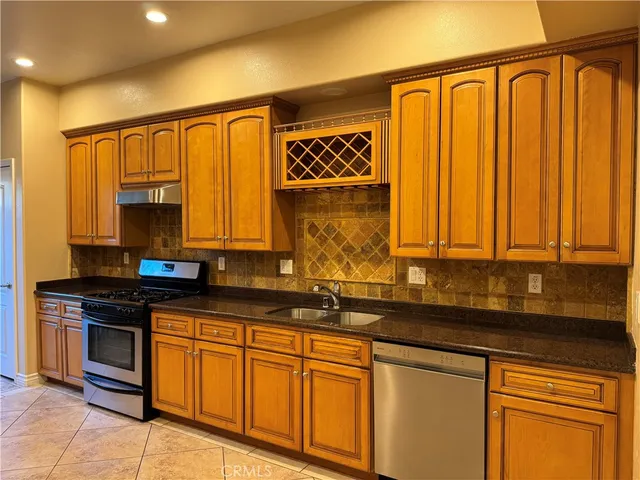a kitchen with stainless steel appliances granite countertop a sink a stove cabinets and a window