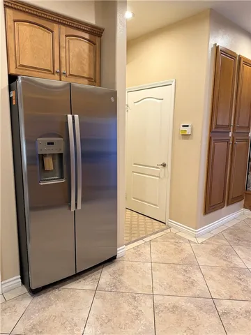 a view of a refrigerator in kitchen and an empty room