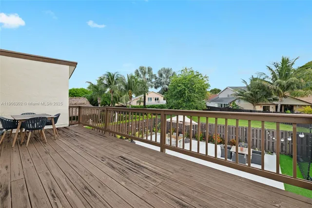 a balcony with wooden floor table and chairs
