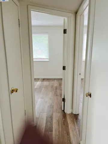a view of a hallway with wooden floor and closet area