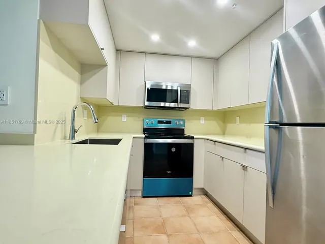 a kitchen with granite countertop a refrigerator and a stove top oven