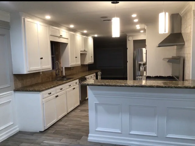 a large kitchen with granite countertop a large counter top sink and stainless steel appliances