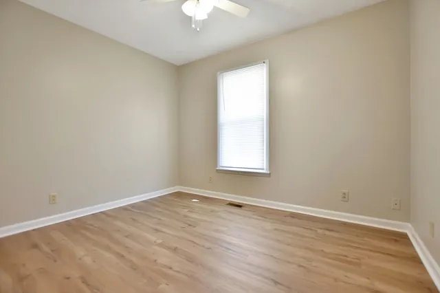 an empty room with wooden floor and windows