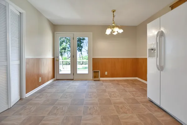 an empty room with chandelier fan and windows