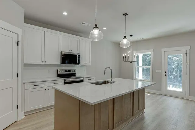 a kitchen with a sink a center island a stove cabinets and a chandelier